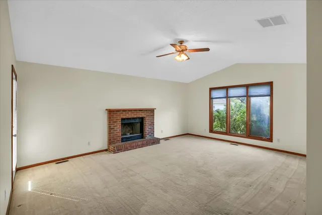 an empty room with windows and fireplace