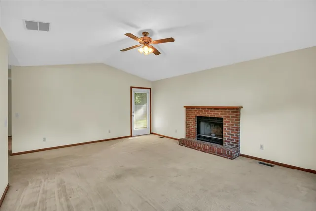 an empty room with windows and fireplace
