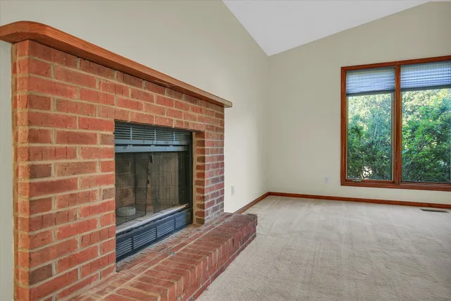 a view of an empty room with a fireplace and a window
