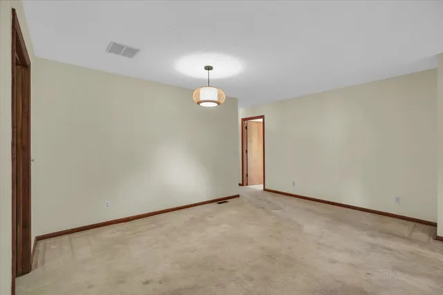 a view of an empty room with a chandelier fan