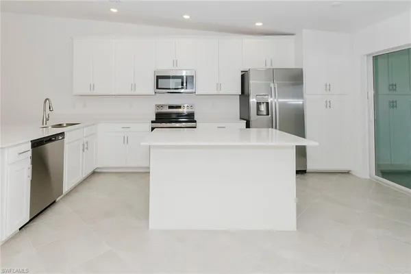 a kitchen with stainless steel appliances a refrigerator sink and white cabinets