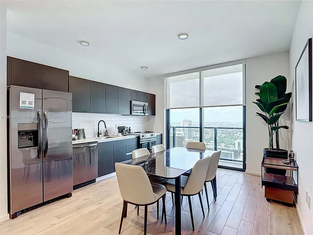 a view of a dining room with furniture a potted plant and wooden floor