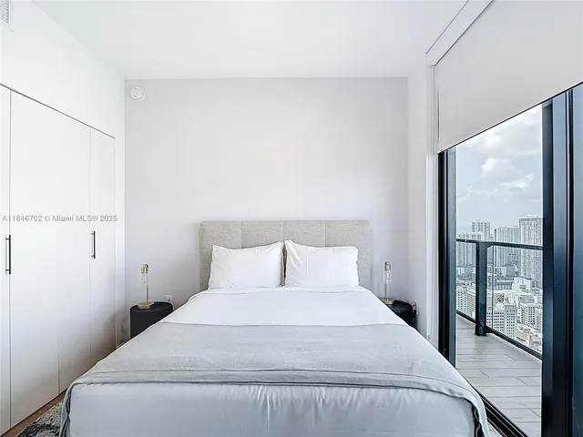 a bedroom with a large bed and a large mirror next to a window