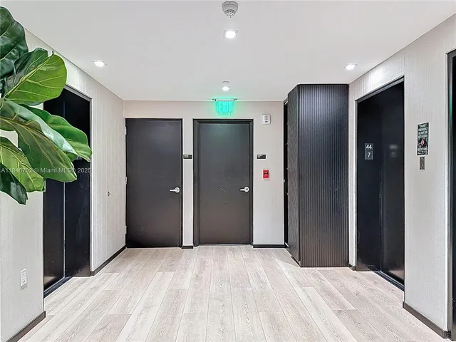 a view of an empty room with wooden floor and a bathroom