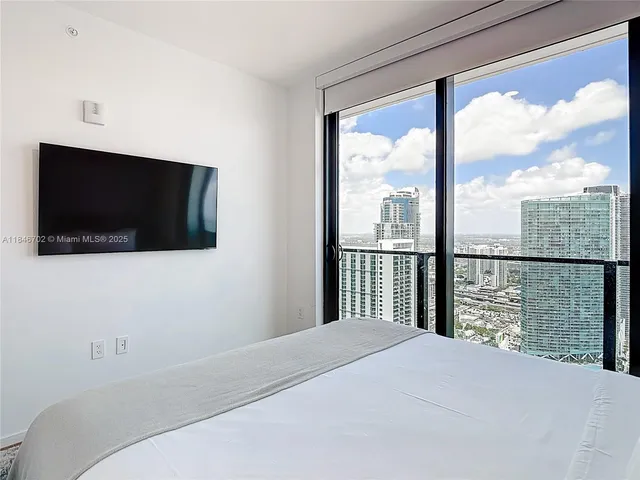a bedroom with a large window and a flat screen tv