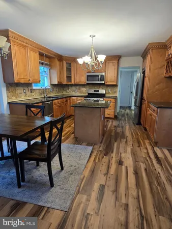 a kitchen with stainless steel appliances granite countertop a stove top oven a sink dishwasher a dining table and chairs with wooden floor