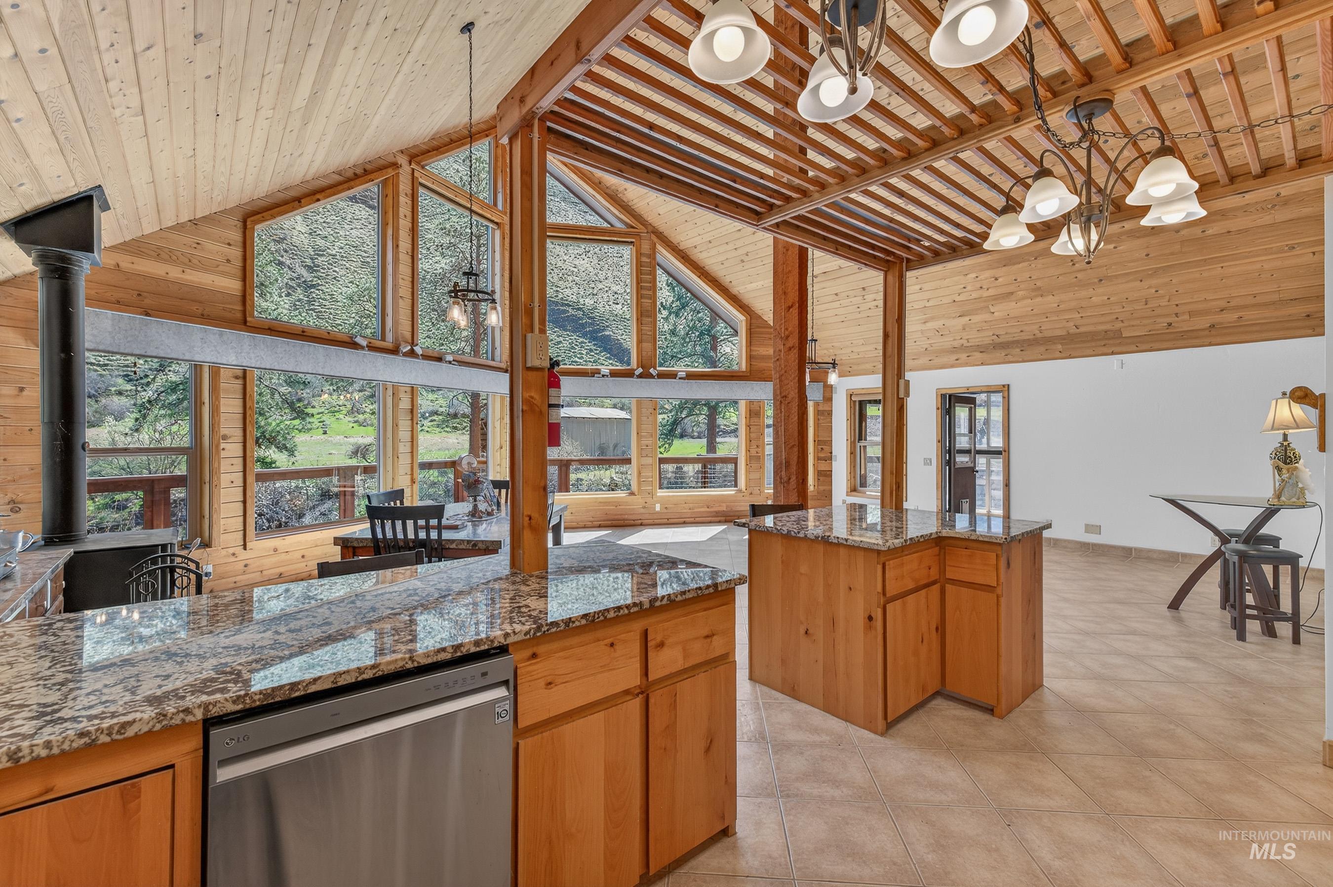 1352 South Main Street Riggins, ID 83549 - Photo 13 of 50 Kitchen with stainless steel dishwasher, dark stone counters, a high wooden ceiling, suspended lighting, and wood walls