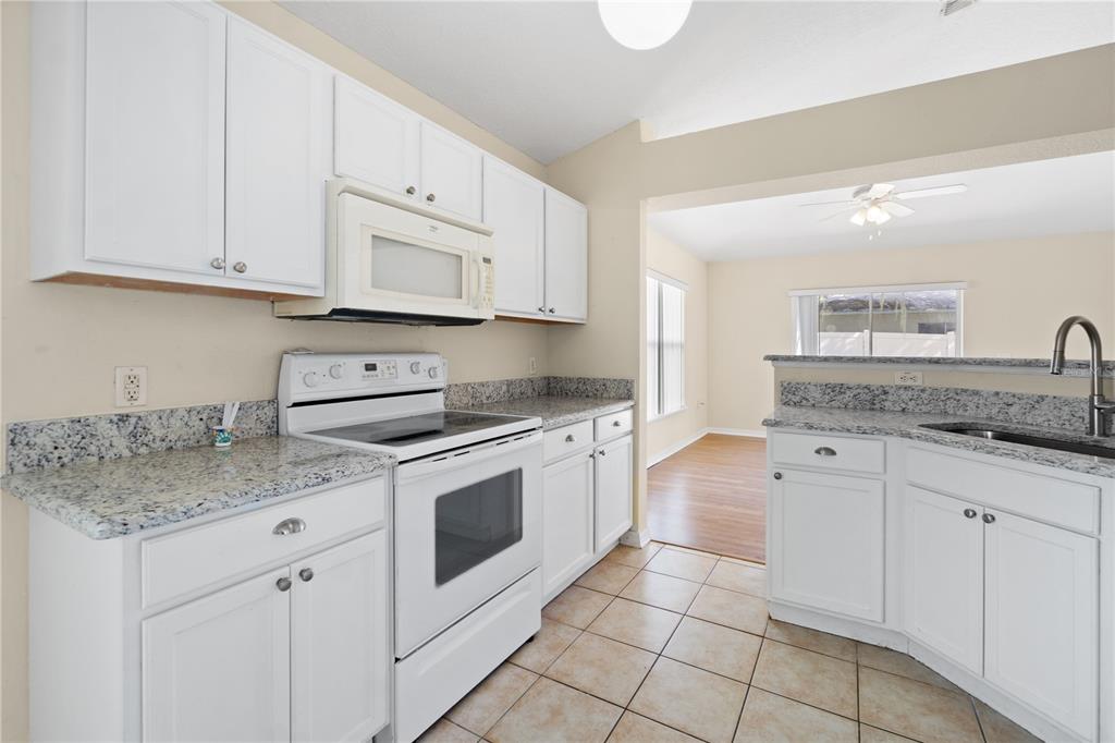 2339 Foxtree Road Tavares, FL 32778 - Photo 11 of 36 a kitchen with granite countertop white cabinets white stainless steel appliances with a sink and dishwasher