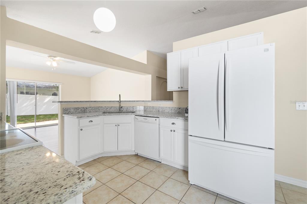 2339 Foxtree Road Tavares, FL 32778 - Photo 13 of 36 a kitchen with granite countertop cabinets and refrigerator
