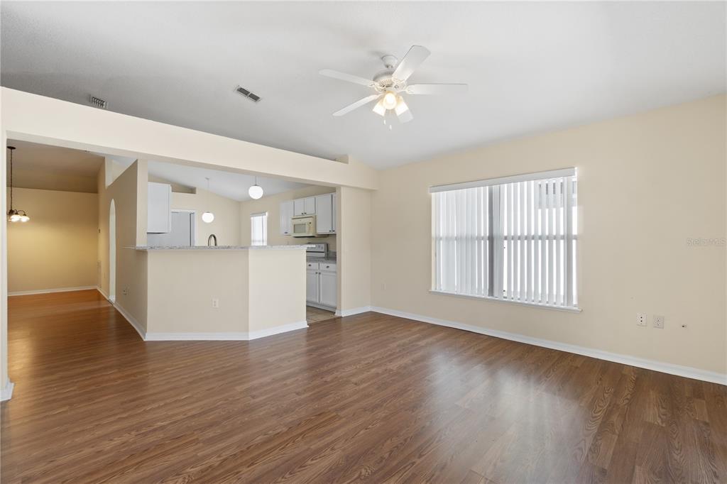 2339 Foxtree Road Tavares, FL 32778 - Photo 14 of 36 a view of an empty room with wooden floor and a kitchen
