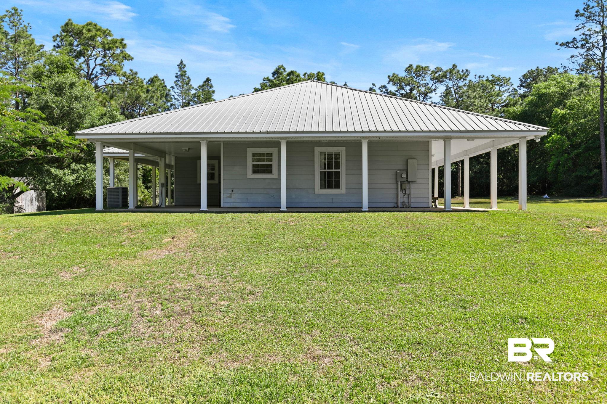 20219 Greek Cemetery Road Robertsdale, AL 36567 - Photo 8 of 41 Light gray siding exterior with a metal roof
