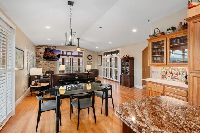 a kitchen with stainless steel appliances granite countertop wooden floor cabinets dining table and chairs