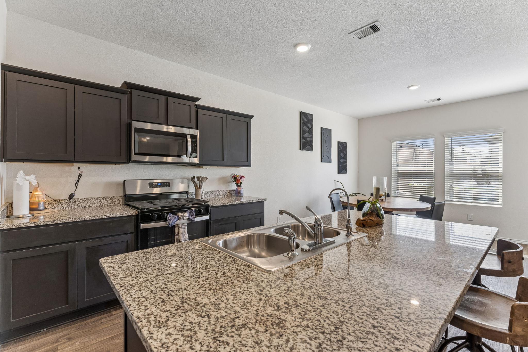 343 Sickle Loop Kyle, TX 78640 - Photo 13 of 40 Kitchen featuring an island with double basin sink, dark wood-finish cabinetry, stainless steel appliances, and granite countertops