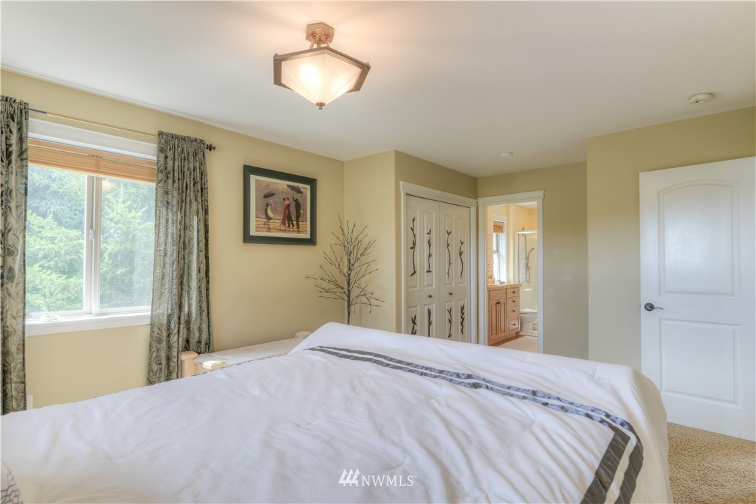 6110 139th Court Southwest Rochester, WA 98579 - Photo 22 of 36 a bedroom with a large bed and a chandelier