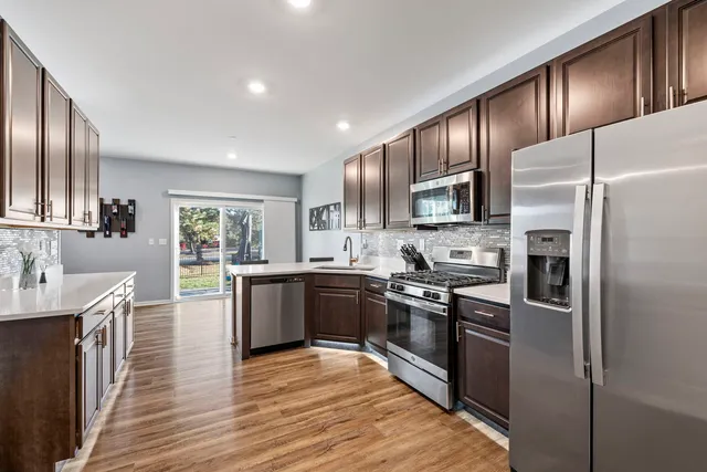 a large kitchen with stainless steel appliances granite countertop a stove refrigerator sink and dishwasher with wooden floor