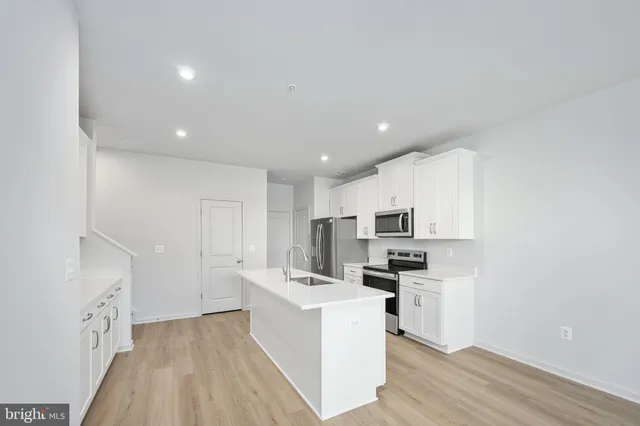 a open kitchen with white cabinets and wooden floor