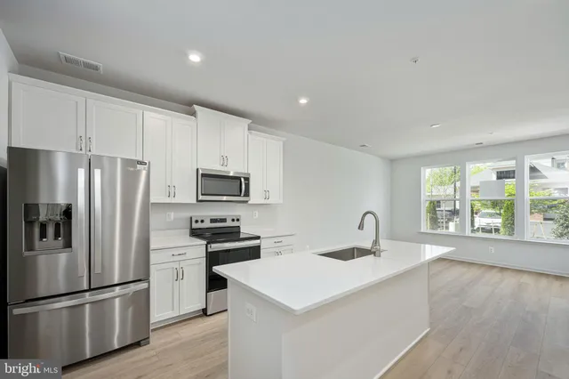 a kitchen with a refrigerator a sink and a stove top oven