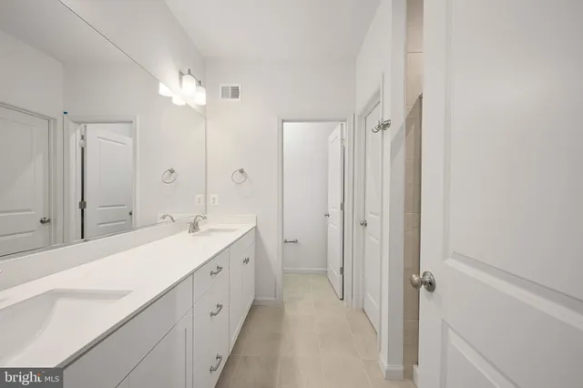 a spacious bathroom with a double vanity sink a mirror and shower