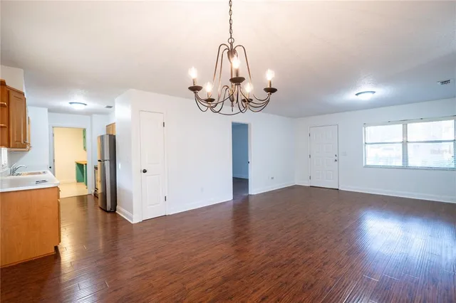 a view of a room with wooden floor chandelier and windows