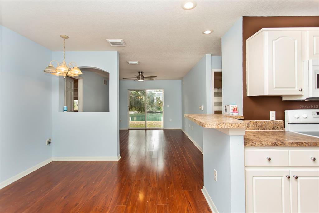 6740 Moonglow Drive, Unit 101 Port Richey, FL 34668 - Photo 6 of 39 a kitchen with a wooden floor and white cabinets