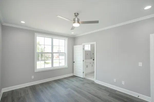 an empty room with wooden floor ceiling fan and windows
