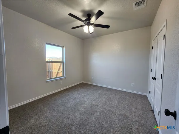 an empty room with ceiling fan and window