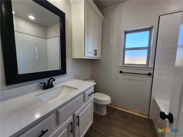 a bathroom with a granite countertop toilet sink and mirror