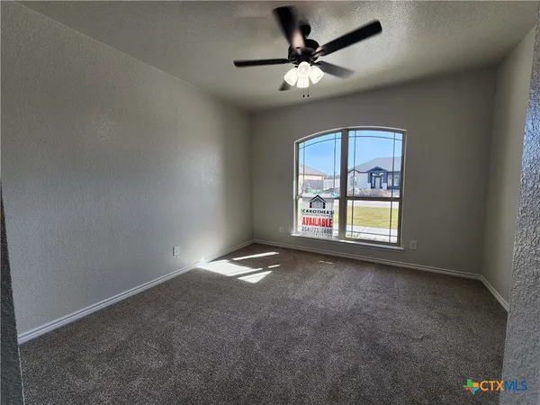 an empty room with windows and fan