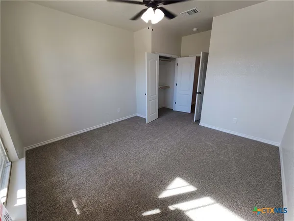 an empty room with a ceiling fan and window