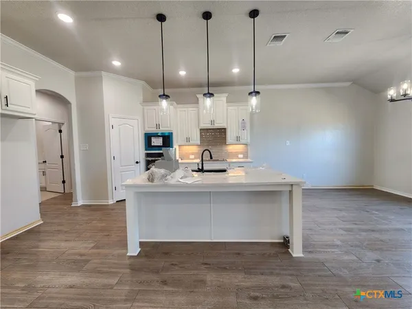 a view of a kitchen with kitchen island a sink stainless steel appliances and cabinets