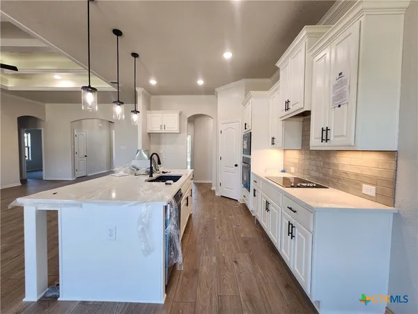 a large kitchen with stainless steel appliances granite countertop a lot of counter space and wooden floors