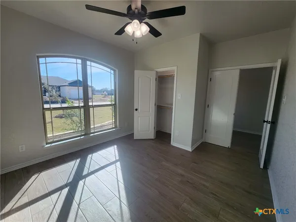 an empty room with wooden floor fan and windows