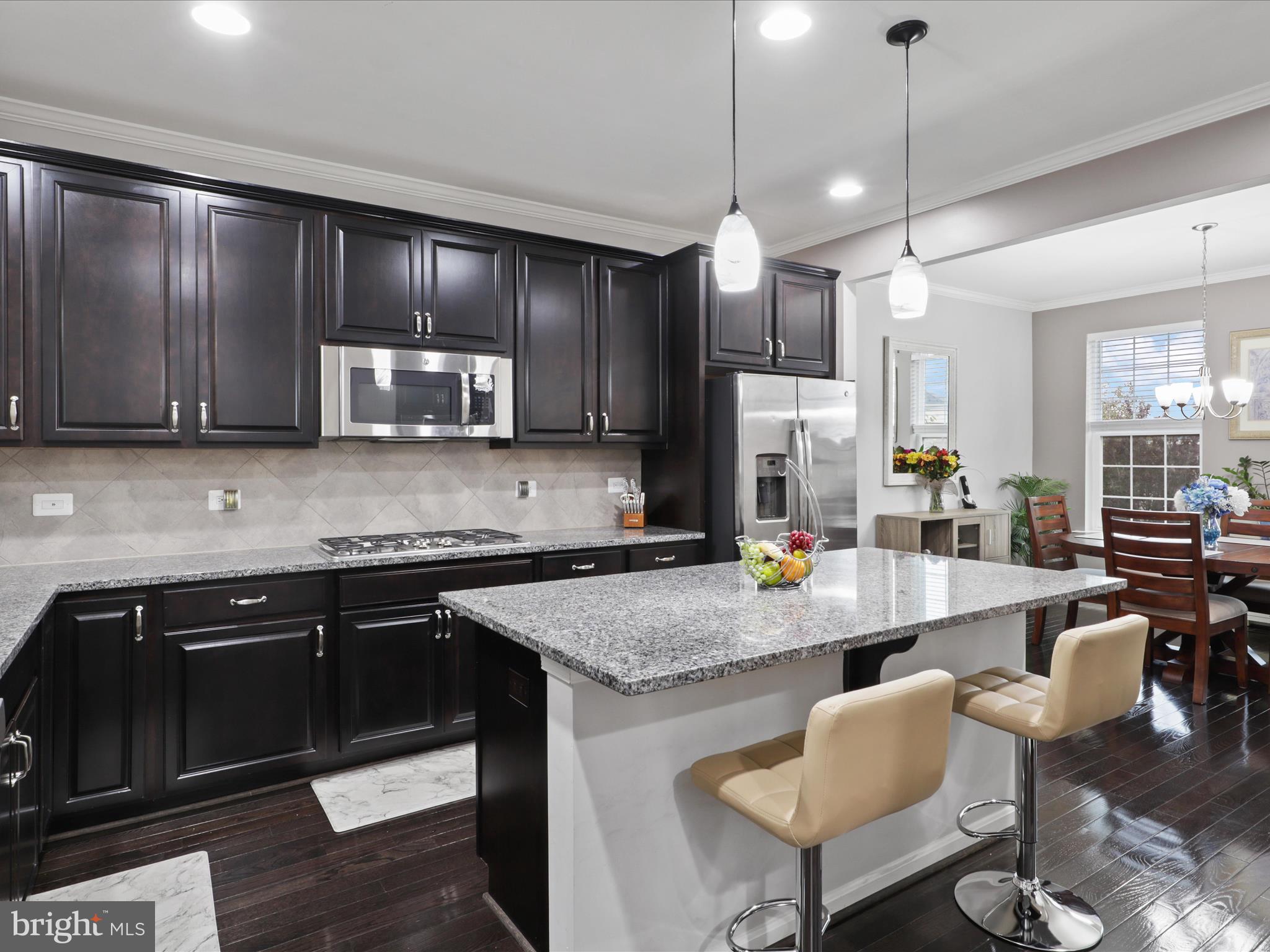 16006 Madison Ridge Place Gainesville, VA 20155 - Photo 14 of 48 a kitchen with stainless steel appliances granite countertop a stove refrigerator a sink dishwasher a dining table and chairs with wooden floor