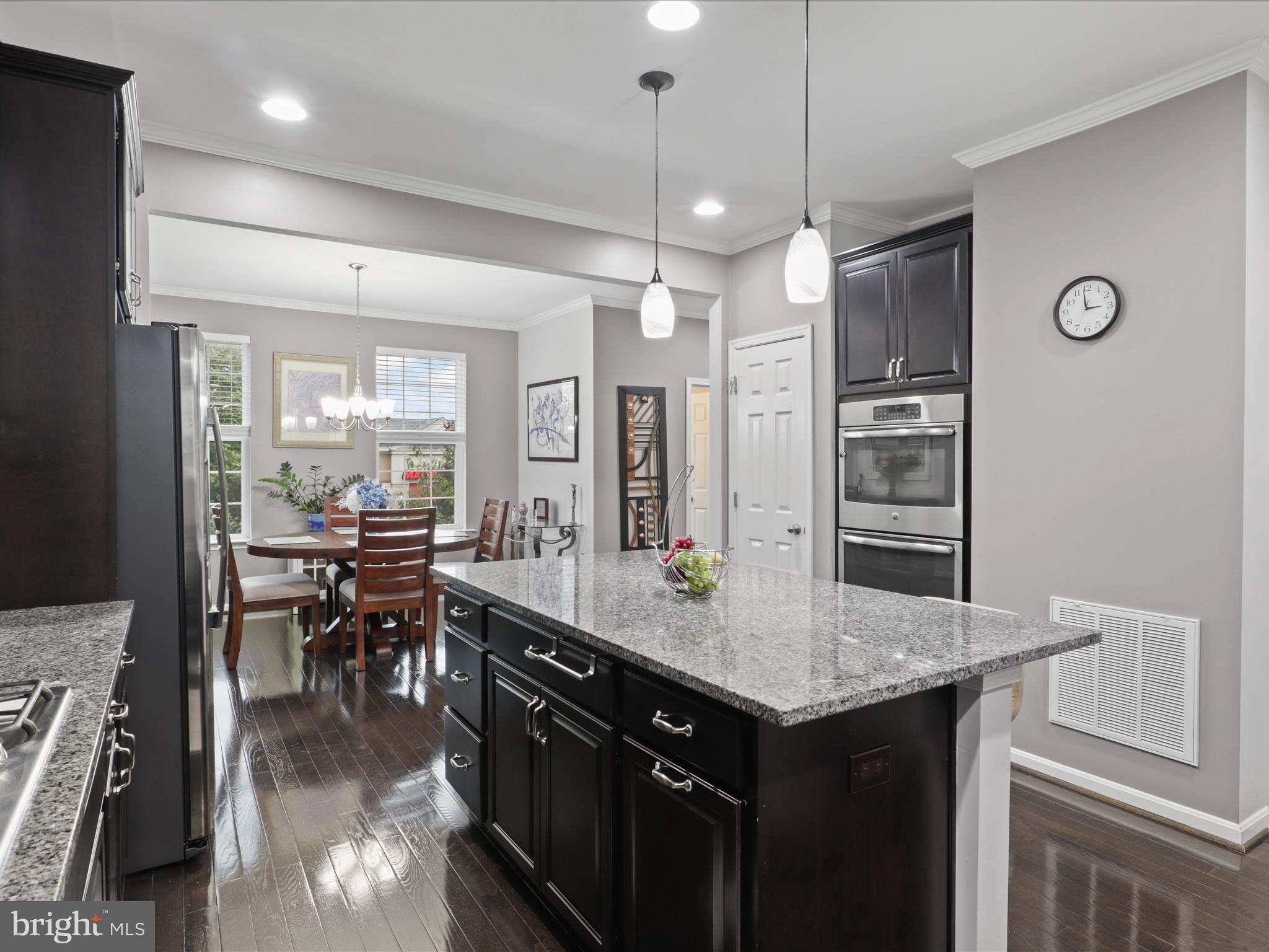 16006 Madison Ridge Place Gainesville, VA 20155 - Photo 18 of 48 a kitchen with granite countertop a stove a refrigerator and a dining table with wooden floor