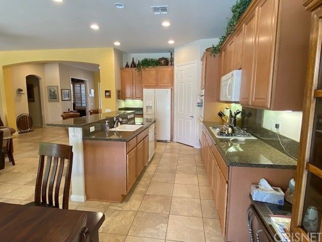 a kitchen with stainless steel appliances granite countertop a sink a stove and a refrigerator