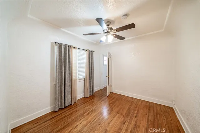 an empty room with wooden floor and a ceiling fan