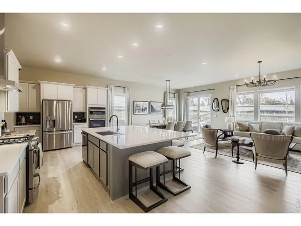 a kitchen with stainless steel appliances wooden floor and chairs