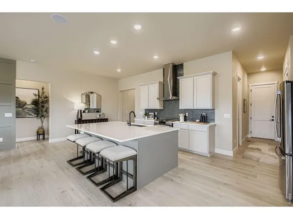a living room with stainless steel appliances furniture a dining table wooden floor and a kitchen view
