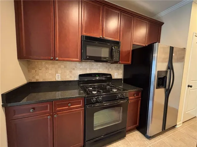 a kitchen with granite countertop wooden cabinets and stainless steel appliances