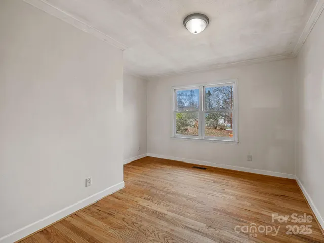 an empty room with wooden floor and window