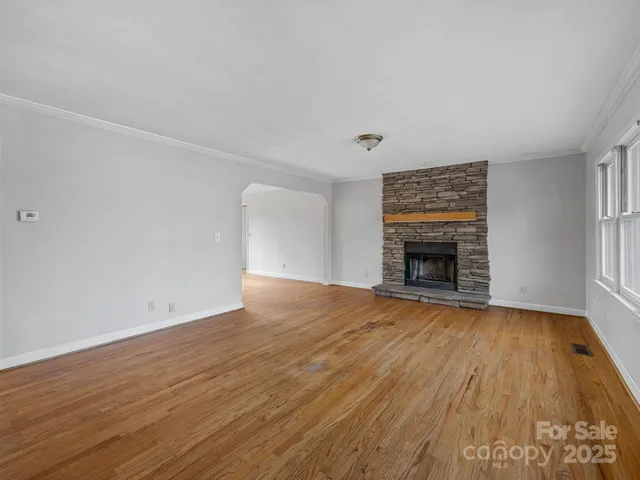 an empty room with wooden floor and a fireplace