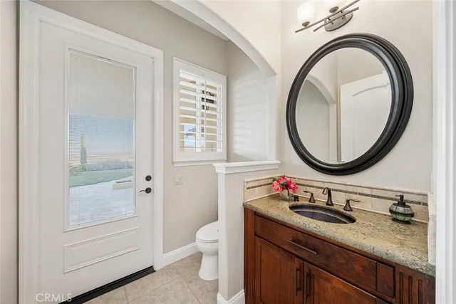a bathroom with a granite countertop toilet a sink and a mirror