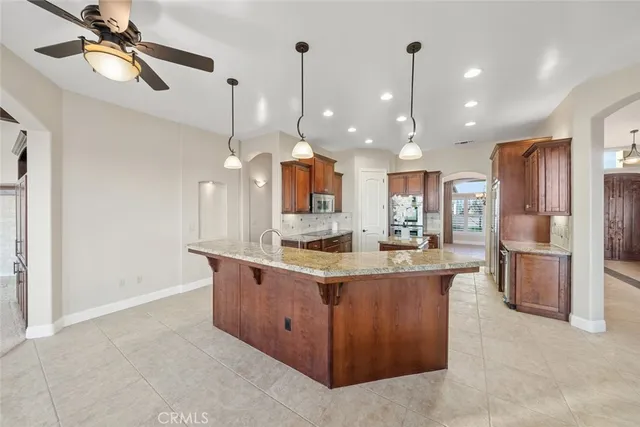 a kitchen with stainless steel appliances kitchen island granite countertop a sink and a refrigerator