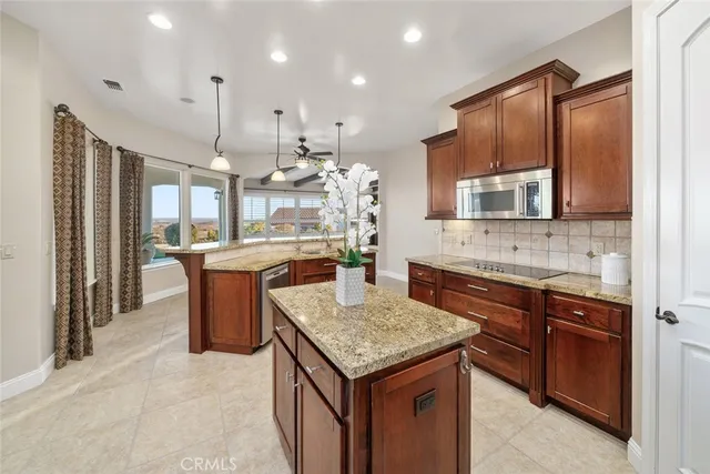 a kitchen with granite countertop kitchen island stainless steel appliances a sink stove and refrigerator