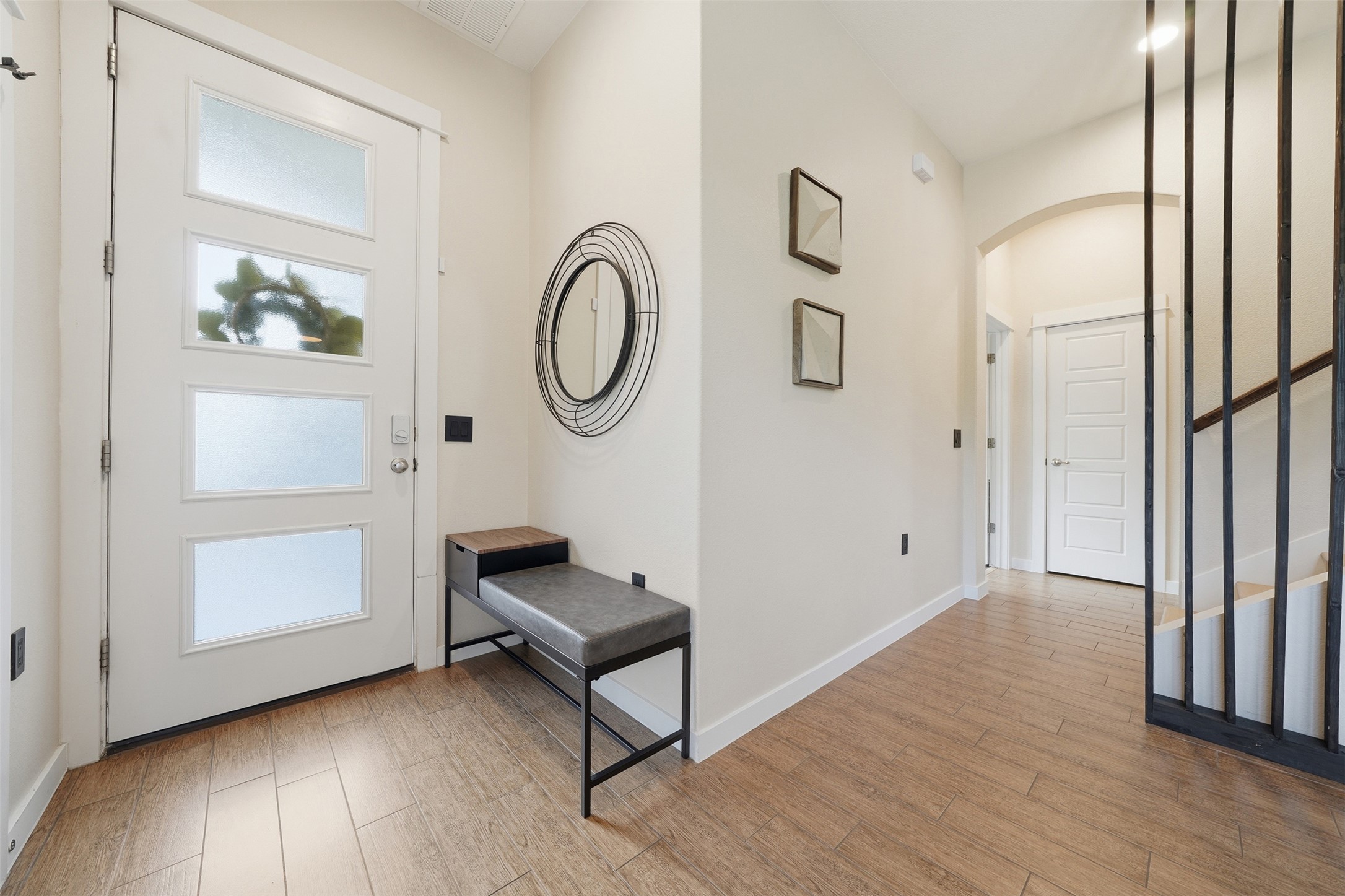 3901 Vaughan Street Austin, TX 78723 - Photo 4 of 37 Entryway featuring a white front door with frosted glass panels, wood-finish flooring, and a modern black metal staircase railing