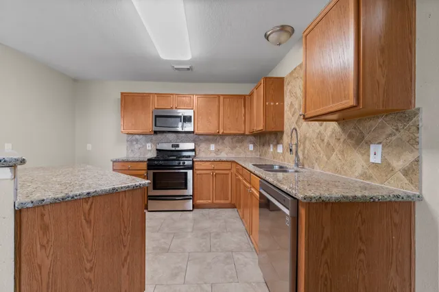 a kitchen with granite countertop a sink stove and cabinets