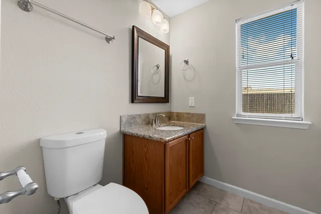 a bathroom with a granite countertop toilet sink and mirror