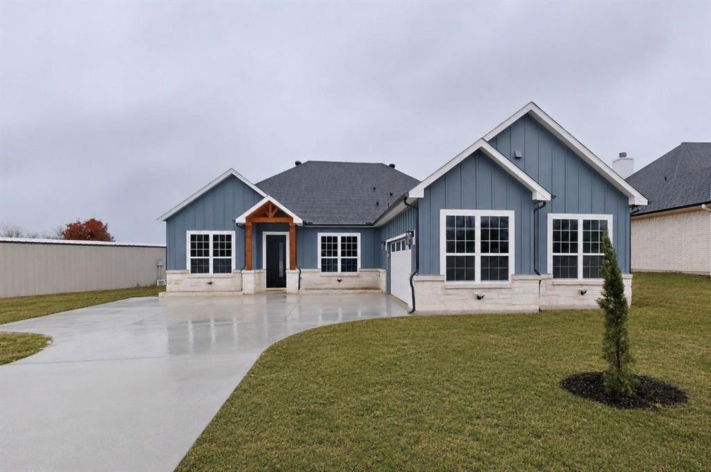 339 Cross Tie Ranch Road Trinidad, TX 75163 - Photo 2 of 29 Contemporary exterior featuring blue board and batten siding, white window trim, stone accents, a dark roof, and a concrete driveway