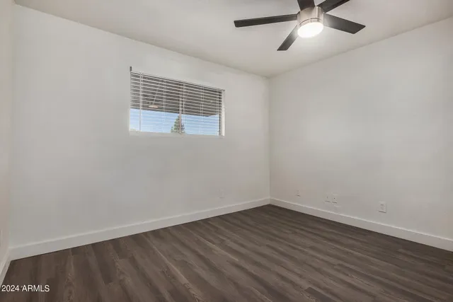 an empty room with wooden floor and a ceiling fan