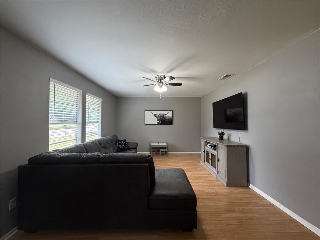 508 Batterson Street Cleburne, TX 76031 - Photo 16 of 28 Living area featuring wood-finish flooring, light grey walls, and a ceiling fan with integrated lighting